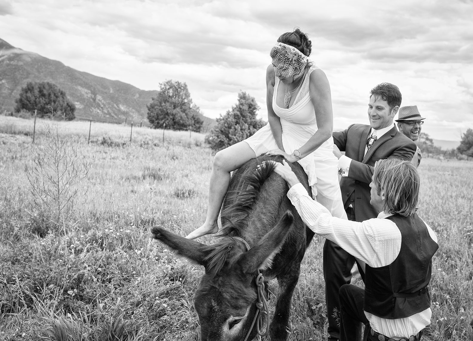 Taos bride gets on donkey with the help of the groom. 
